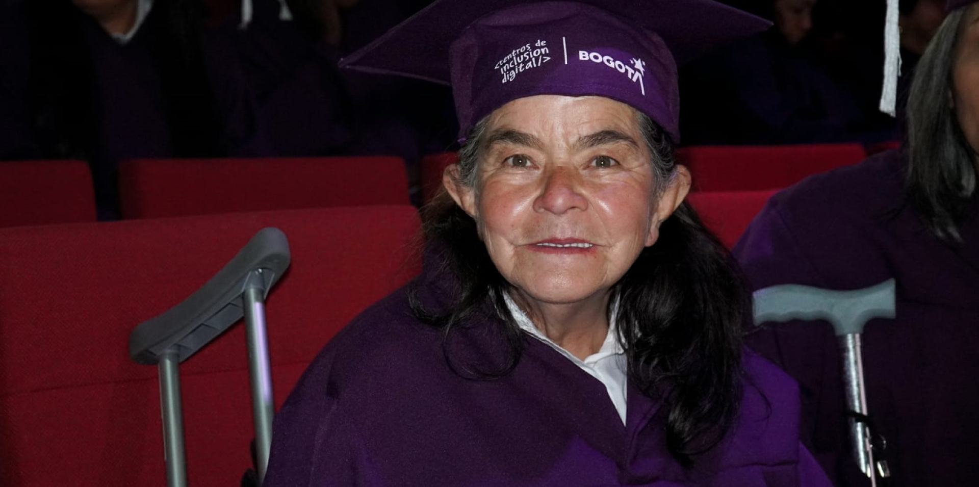 Mujer mayor con toga y birrete en ceremonia de graduación de centros de inclusión digital