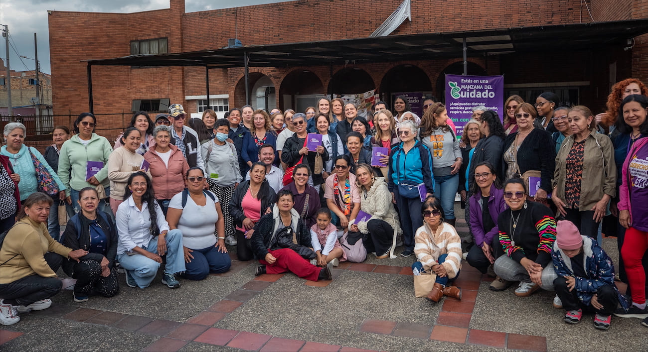 Grupo demmujeres en frente de la Manzana del Cuidado posando para foto