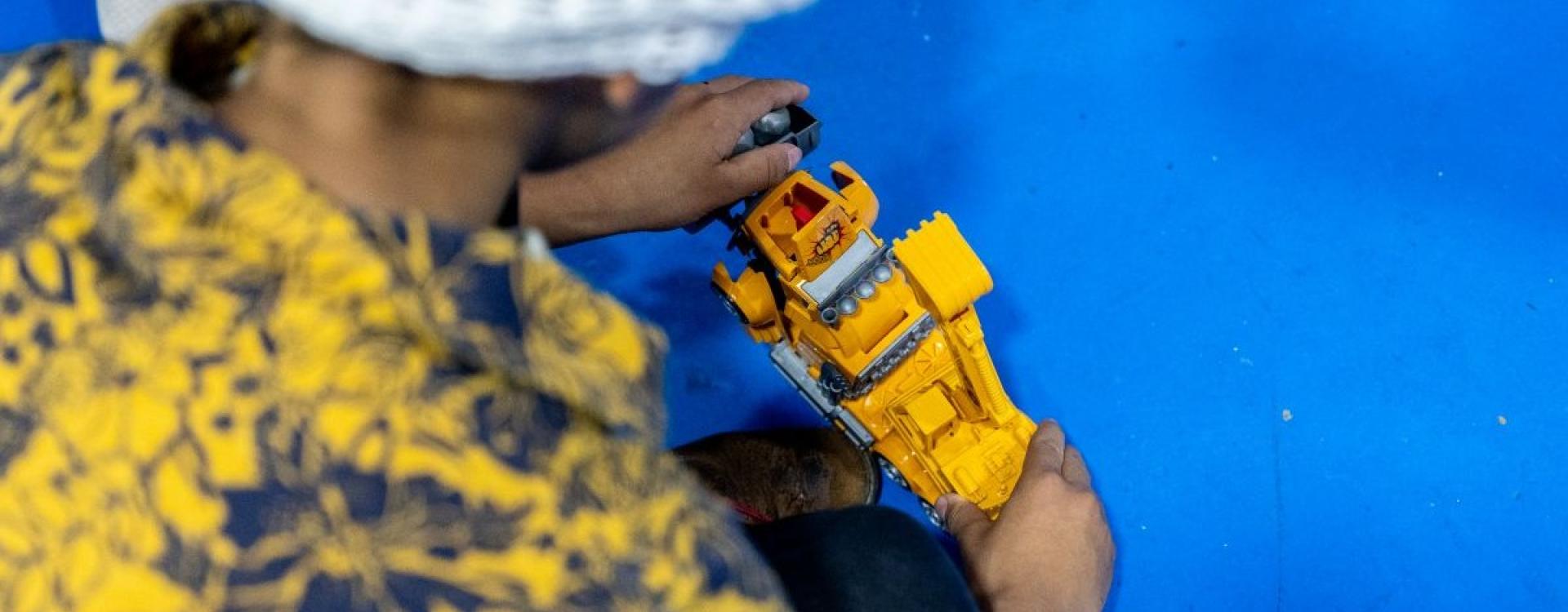 Niño con gorro rojo jugando con un juguete