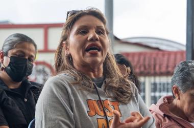 Mujer de buso gris hablando junto a otras mujeres